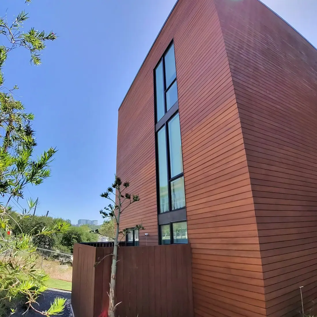 Modern wood clad home with full height windows on a hillside lot