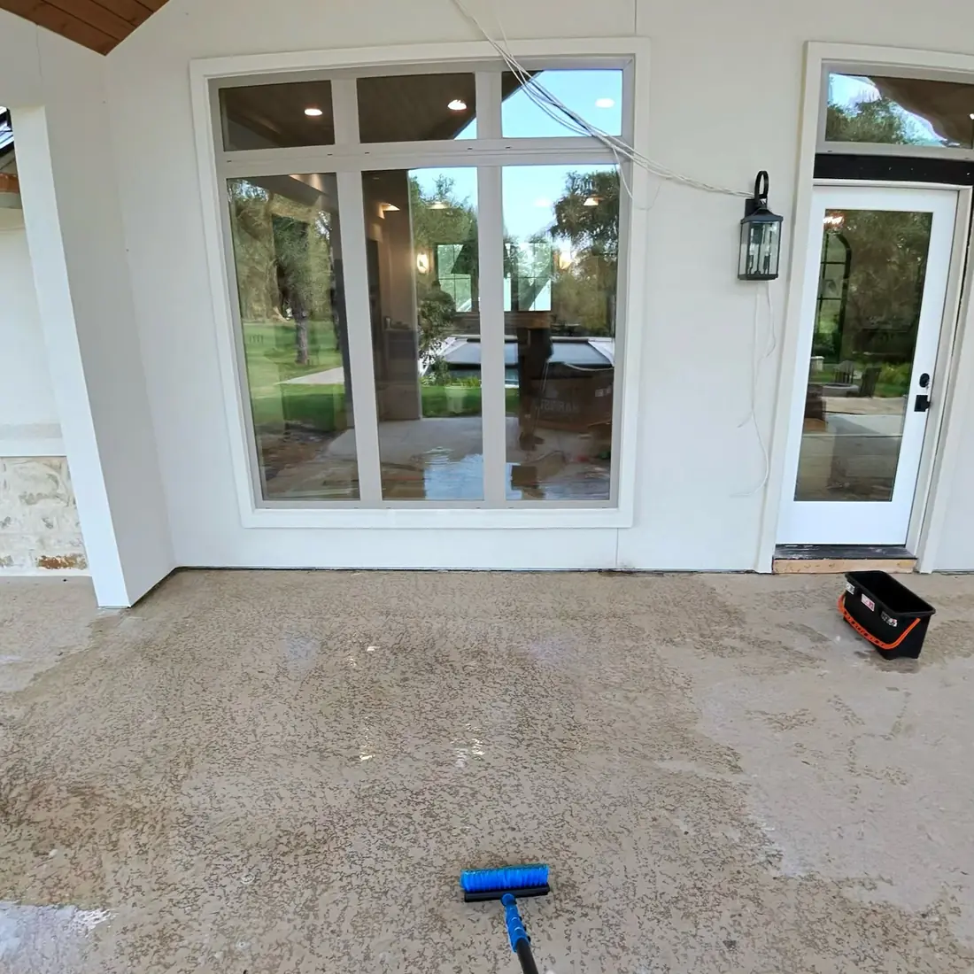 Newly built home with large windows and an unfinished patio during a construction clean
