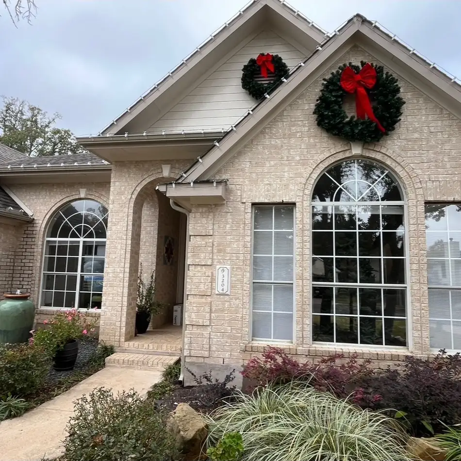 Brick home with arched windows dressed with holiday wreaths