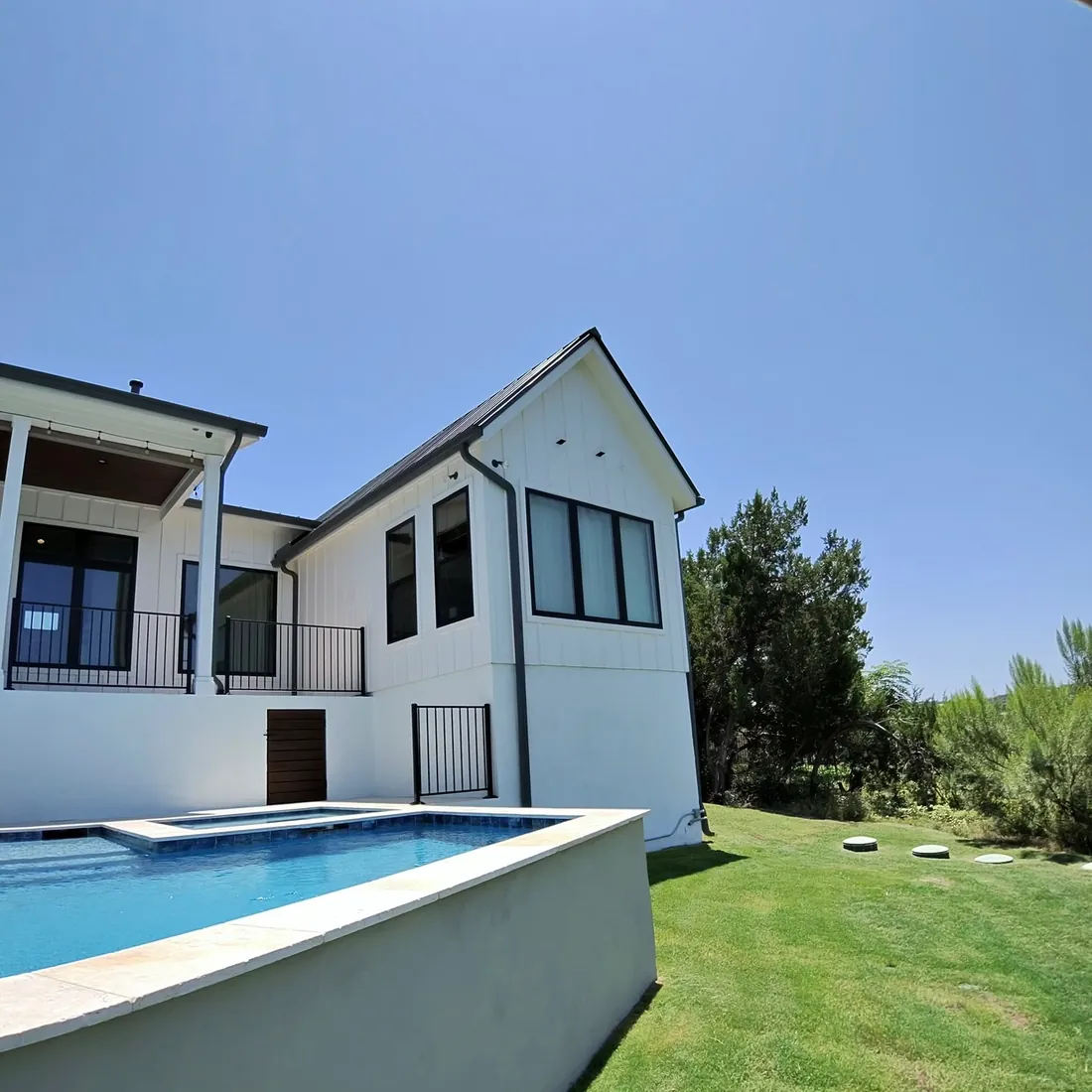 White farmhouse with a pool and black framed windows