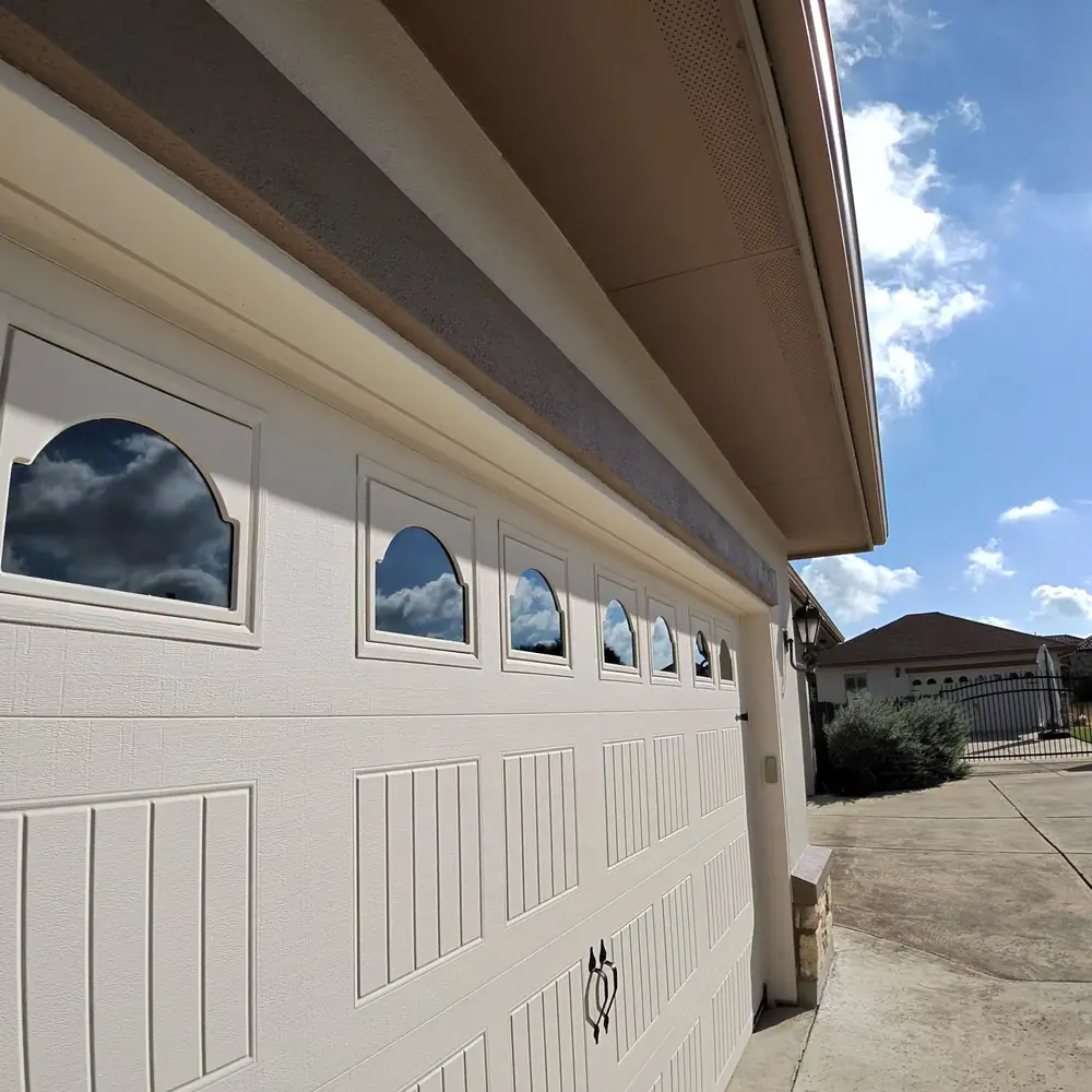 Row of arched decorative windows along a white garage door, each pane reflecting the sky