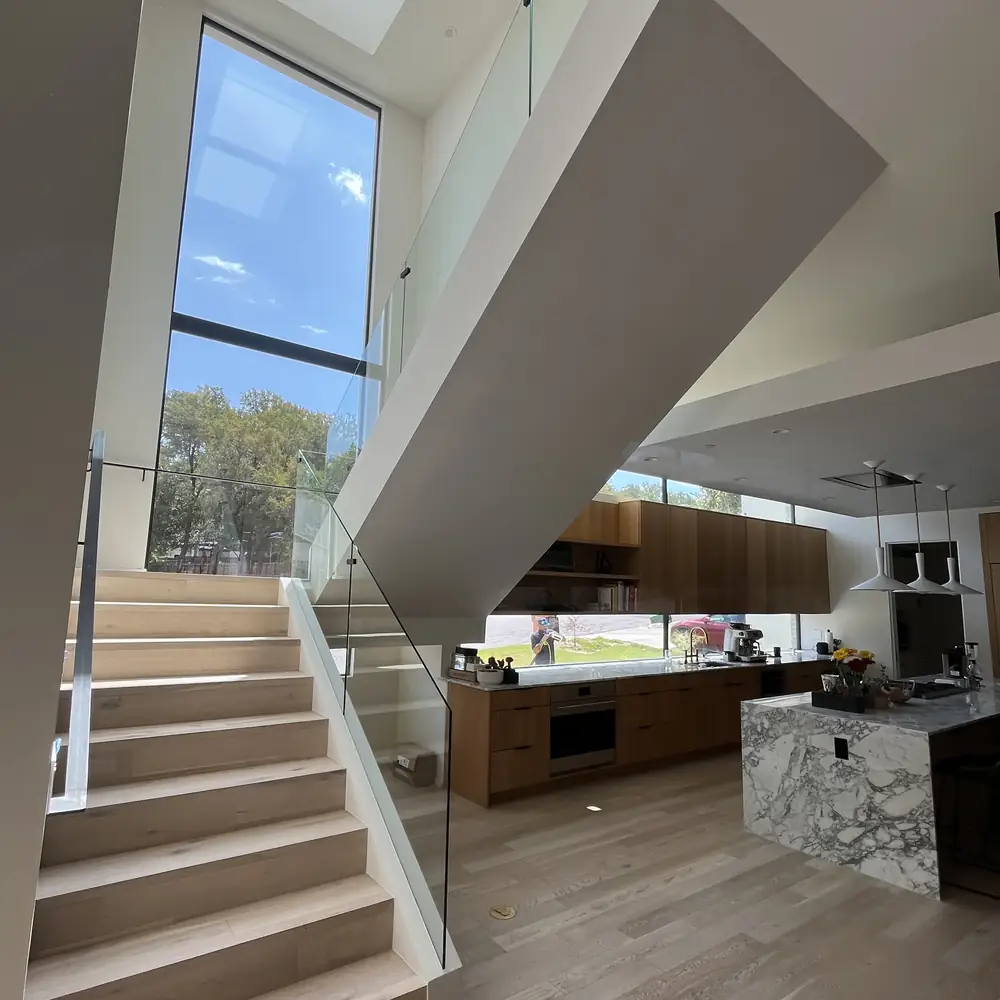 Modern staircase beneath a skylight, with glass running up to the landing