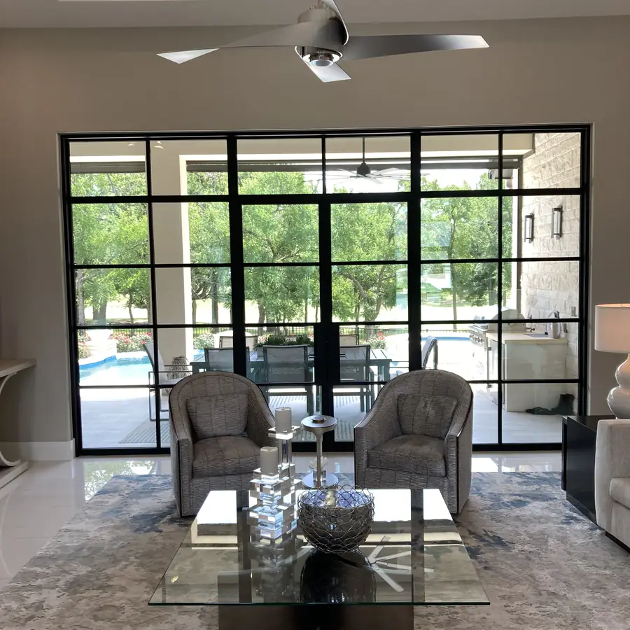Living room looking out through a wall of steel framed glass doors to the pool