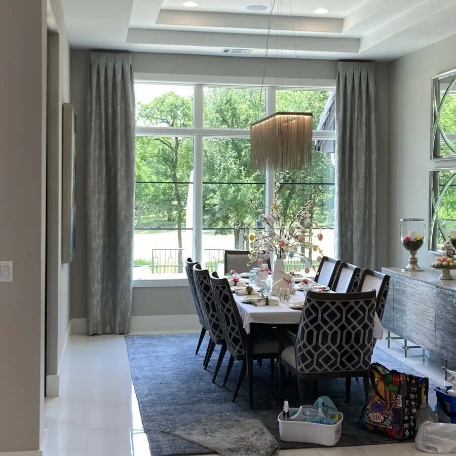 Dining room framed by a tall window onto the garden, full length curtains either side