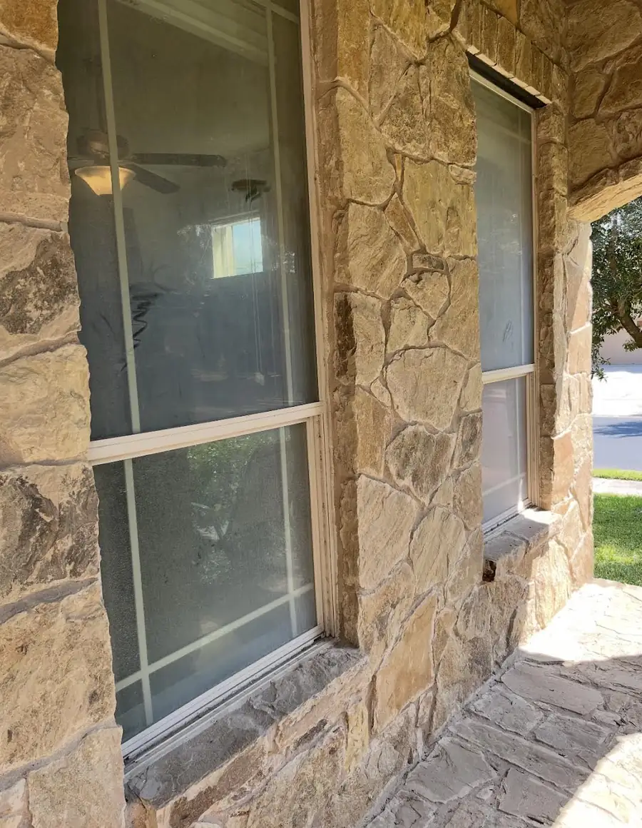 Stone framed windows covered in hard water film, the glass clouded to the point of looking frosted
