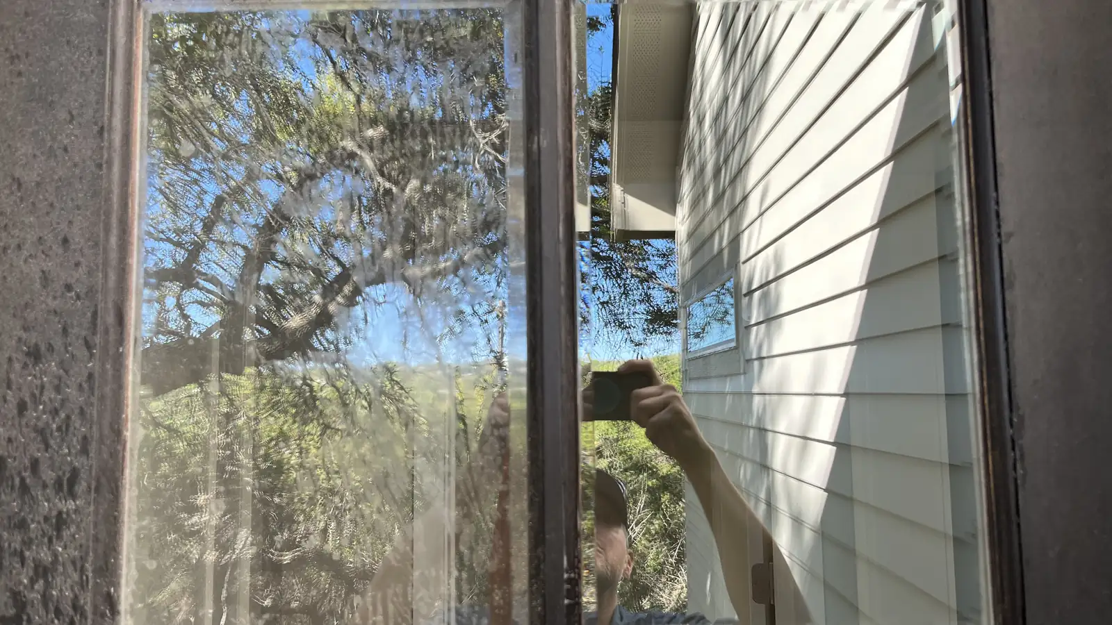 A wooden French door part way through hard water removal, left pane still under mineral film, right pane cleaned clear