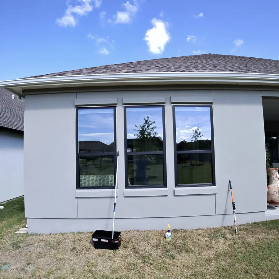 Curved bay of windows on a stucco elevation, water fed pole set up on the grass