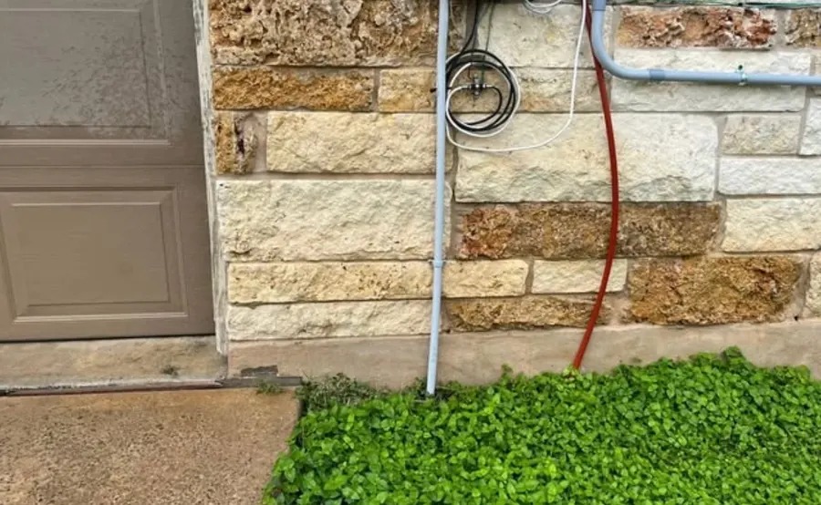 The same limestone courses beside the garage door after a soft wash, the stone back to its natural cream and tan